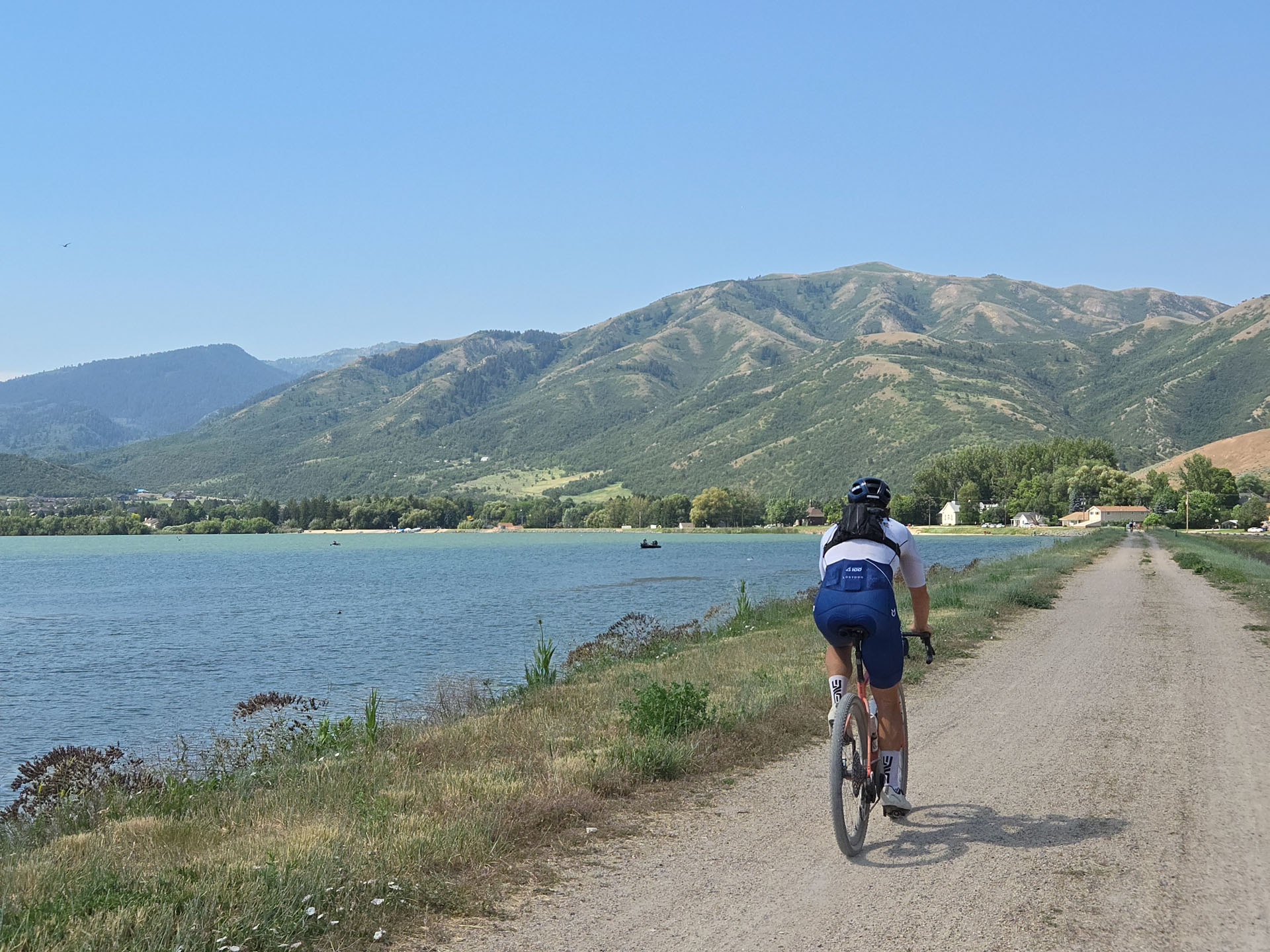 Rider on the bike path along Mantua Reservoir, big mountains across the water