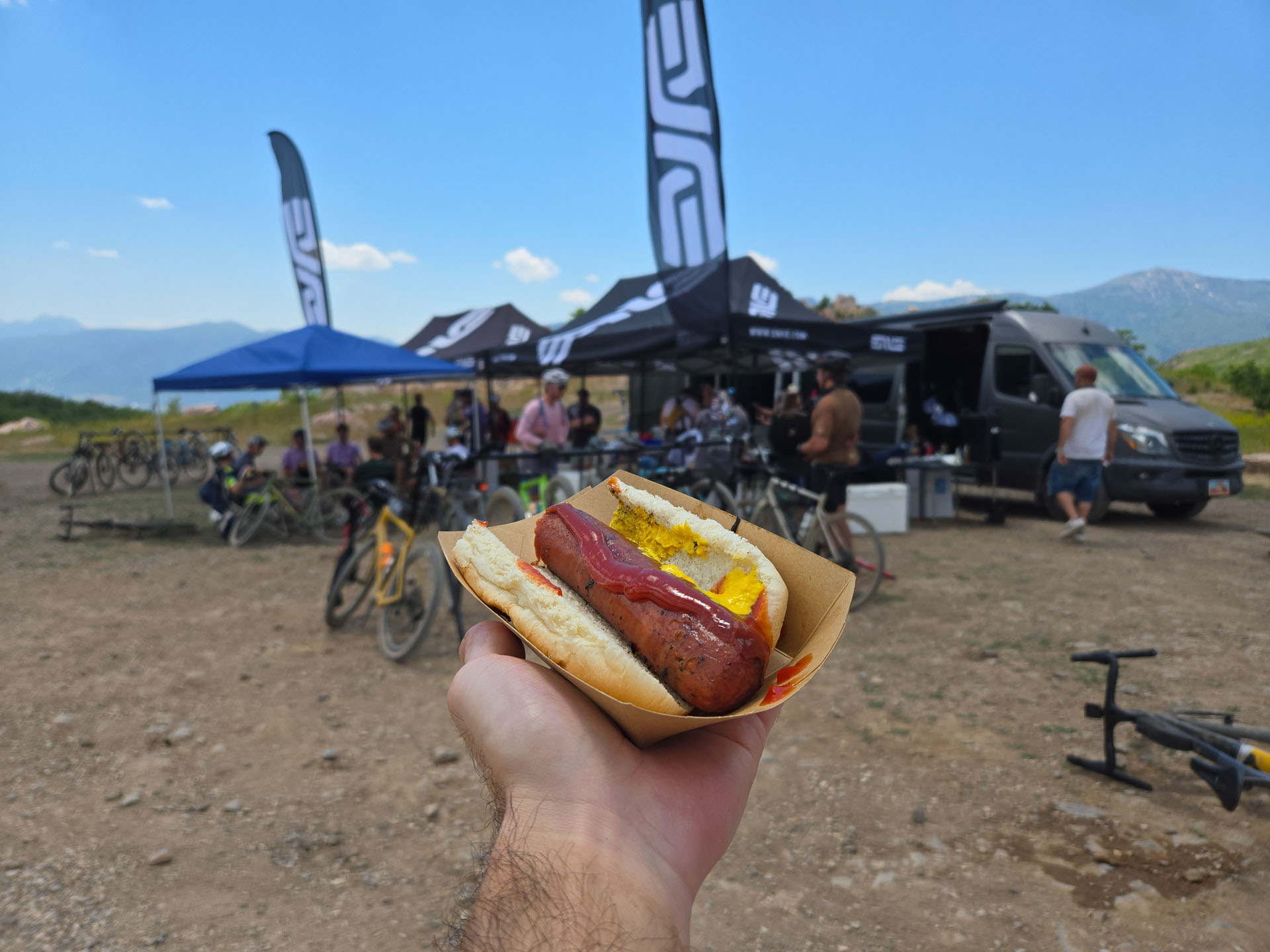 The long-promised hot dog, held up in front of the ENVE aid-station tents