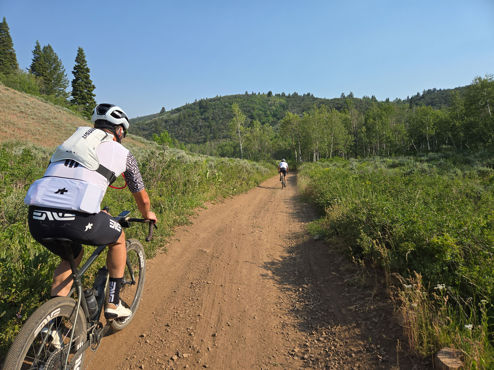 Rider on the gravel path descending toward the finish, mountains in the background